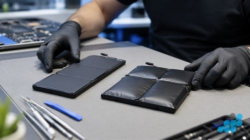 OEM-grade Dell replacement battery beside a swollen original on the celltech bench